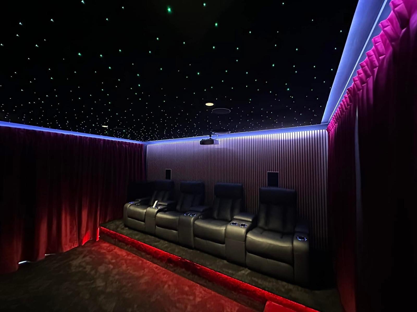 Home theatre seating with red acoustic curtains and starlight ceiling